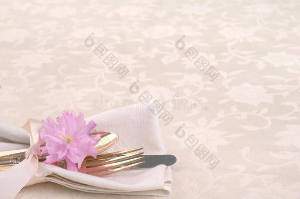 在奶油桌布上放着叉子，刀，勺子，樱花