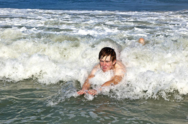 一个十几岁的<strong>男孩</strong>在海浪中<strong>冲浪</strong>