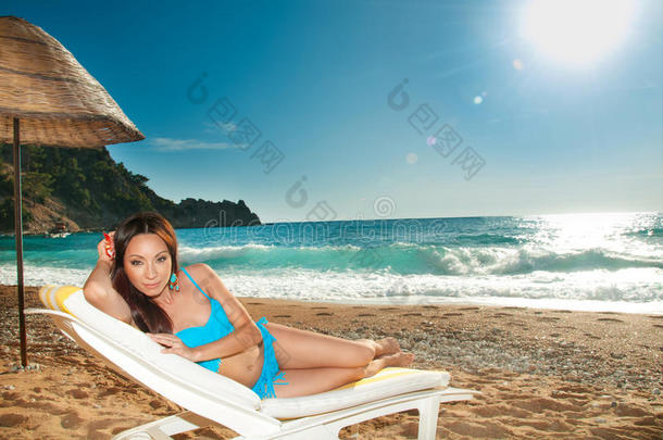 美丽的黑发女孩在海边晒太阳