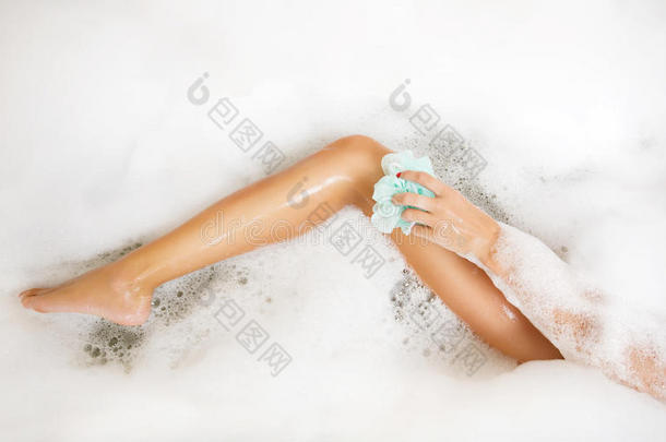女人在浴缸里洗腿时用了很多泡泡泡泡浴。