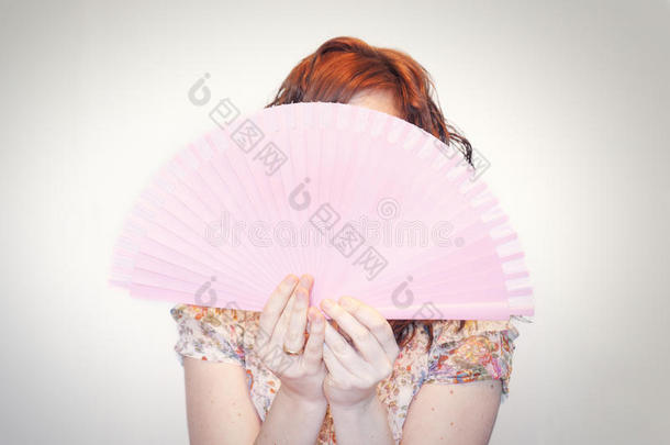 一位女士正在展示一把粉红色的西班牙<strong>折扇</strong>