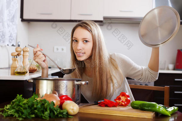 普通的金发女人拿着勺子煮汤