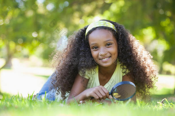 公园里拿着放大镜的小女孩对着镜头微笑