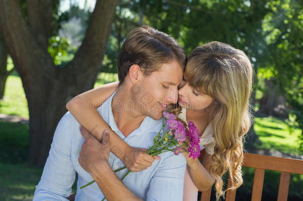 一对可爱的情侣在公园里拥抱，女孩捧着花