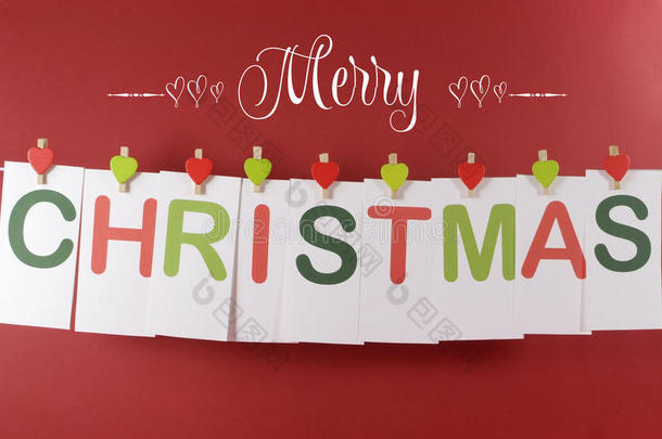 圣诞快乐<strong>祝福语</strong>横穿红绿字母卡片挂在心形钉上，挂在一条线上