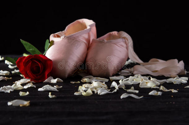 地板上放着玫瑰花瓣的旧芭蕾拖鞋