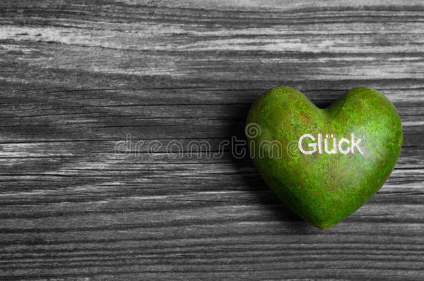 绿色心形，灰色木质背景上有德语“幸运”一词。