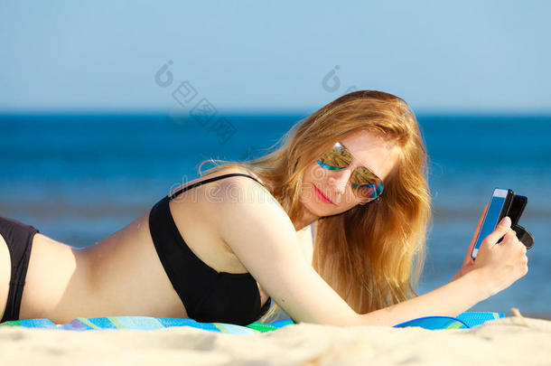 暑假女孩在海滩上用电话晒太阳