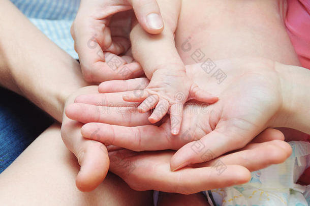 妈妈和爸爸牵着刚出生的婴儿的手