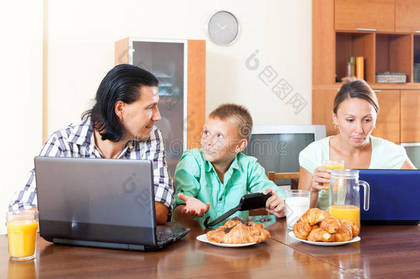 一家人早上用笔记本电脑和果汁吃早餐