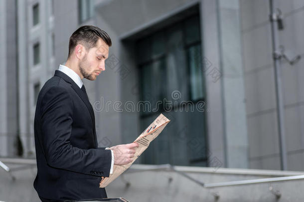 坏消息。一个商人在读一份金融报纸的侧视图。读商业新闻的大胡子男人。