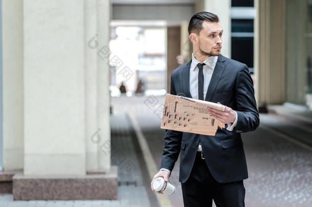一天的计划。一个年轻人站在街上看报纸。在办公中心喝咖啡的商人。