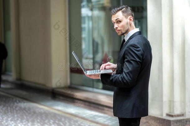 <strong>全力以赴</strong>地工作。成功的商人拿着笔记本电脑站在街上