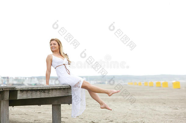 坐在海滩上穿着白裙子的年轻女子