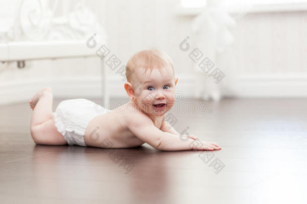 快乐的七个月大的小女孩在硬木地板上爬行