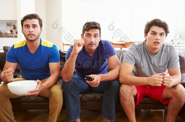 一群男人坐在沙发上看体育比赛