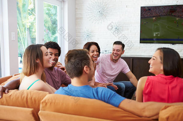 一群朋友坐在沙发上看足球