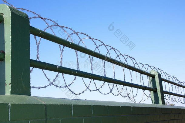 绿色彩绘砖墙顶上的卷曲铁丝护栏