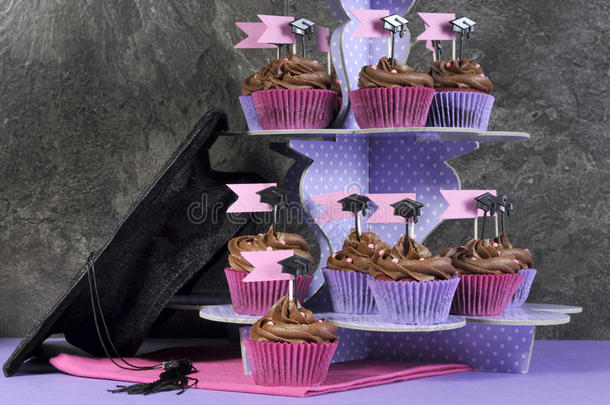毕业典礼当天粉色和紫色的派对纸杯蛋糕和大帽子。