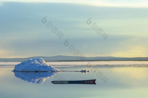 夕阳下，春山湖上冰山融化的背景上，一艘旧船。