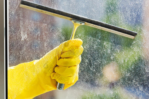 手戴黄色手套用橡皮刷擦窗户
