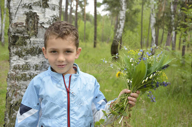 拿着一束花站在树林里的男孩。