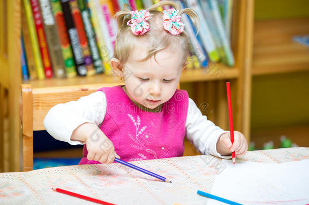 可爱的小女孩在幼儿园桌边用彩色铅笔画画