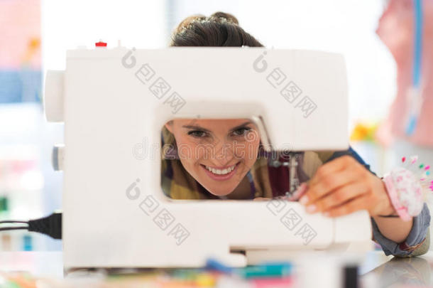 微笑的女裁缝在缝纫机上工作