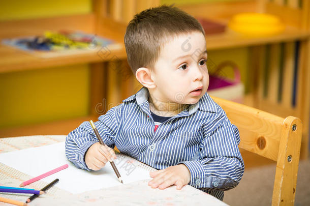 <strong>幼儿园</strong>小男孩在<strong>幼儿园</strong>桌边用彩色铅笔画画