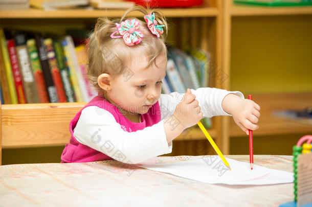 可爱的小女孩在<strong>幼儿园</strong>桌边用彩色铅笔画画