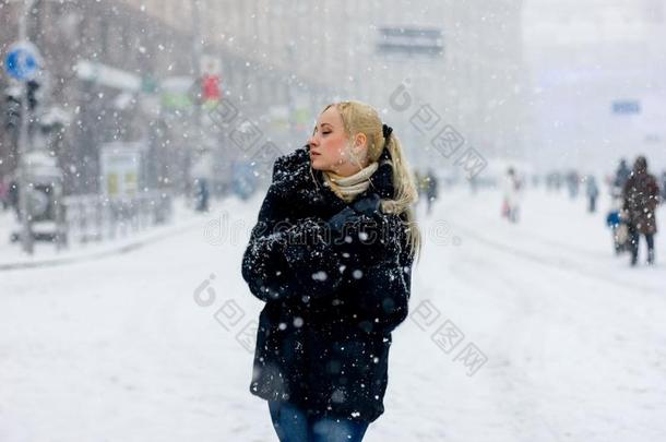 穿着毛皮大衣走路的金发女人。 降雪。