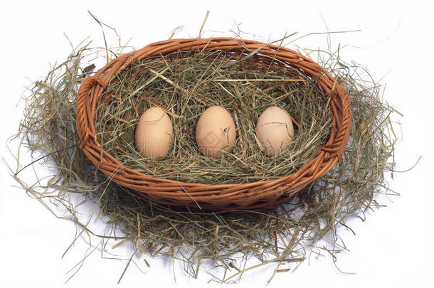 三个有机鸡蛋放在干草上的柳条篮子里