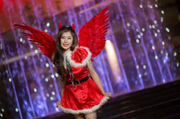 美丽的亚洲女孩穿着圣诞老人的服装，带着夜光过圣诞节