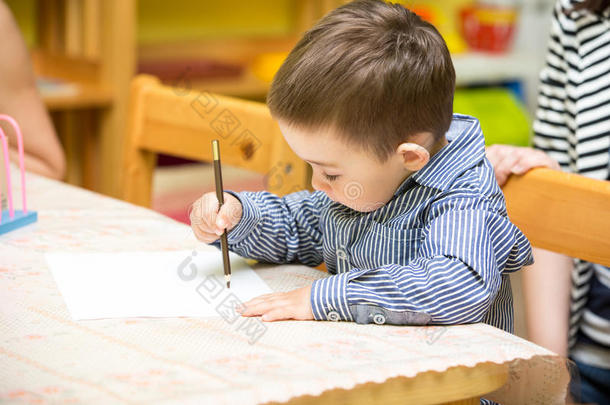 幼儿园小男孩在幼儿园桌边用<strong>彩色铅笔画</strong>画