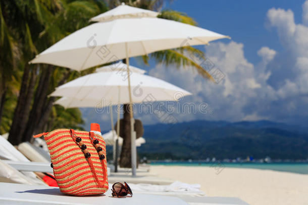 热带海滩上的包、太阳眼镜和防晒霜