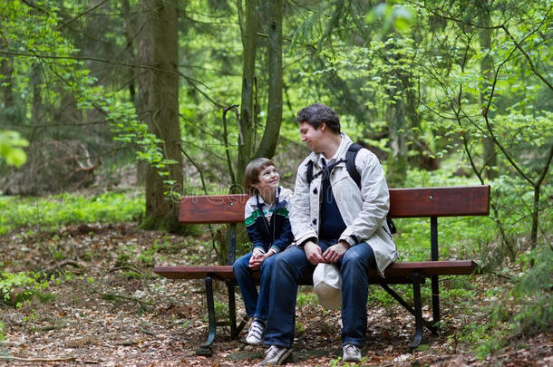 父子俩在树林里徒步旅行后在长凳上休息