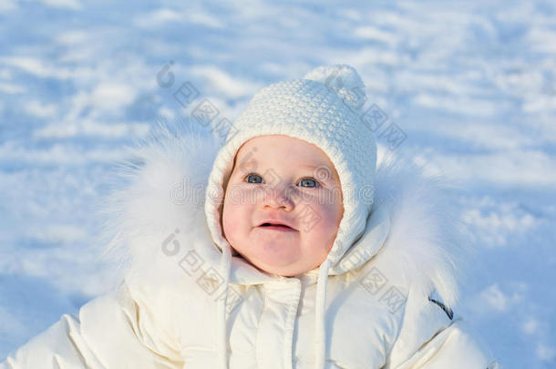 可爱的小女孩穿着白色夹克坐在外面一个阳光明媚的冬天
