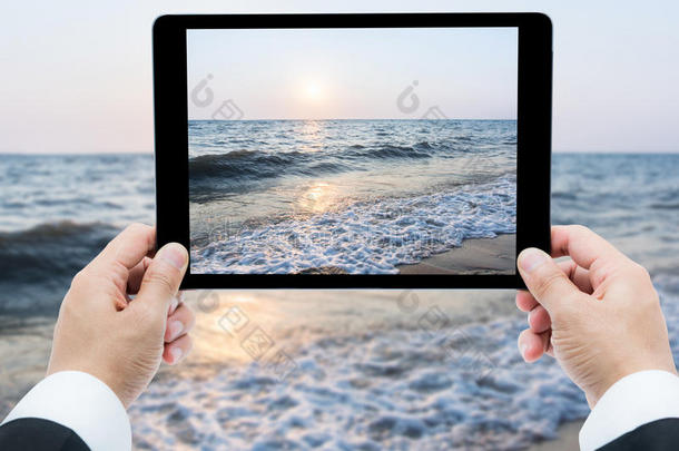 商人手拿平板<strong>电脑</strong>拍海滩和大海