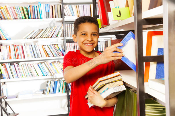 手放在书架上的快乐男孩有很多书