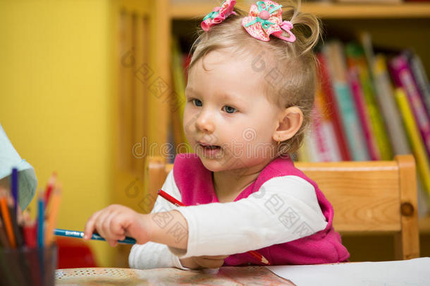 可爱的小女孩在<strong>幼儿园</strong>桌边用彩色铅笔画画