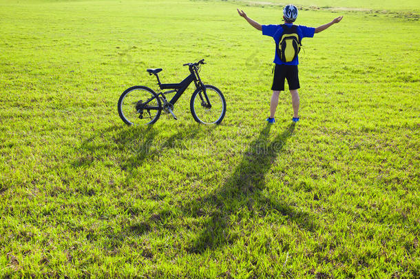 骑着自行车在草地上放松的年轻背包客