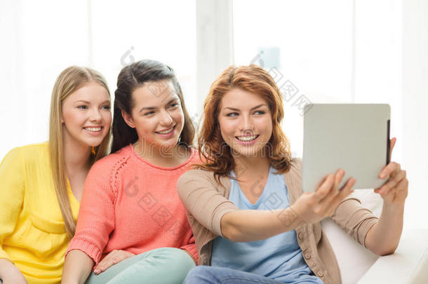 三个笑容满面<strong>的</strong>少女在家里拿着平板电脑
