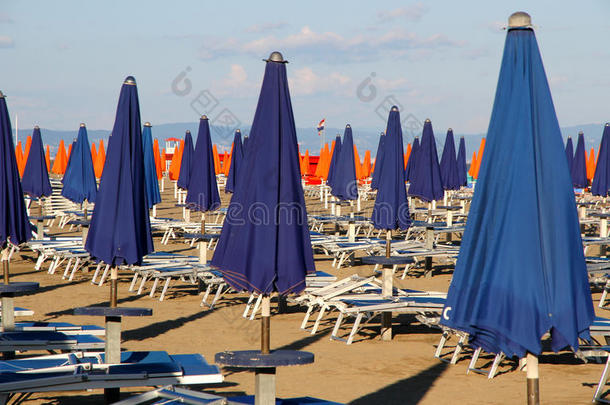 阳光普照的海滩上，蓝色和橙色的雨伞