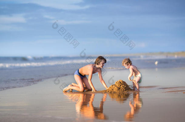 有趣的小女孩和她弟弟在海滩上