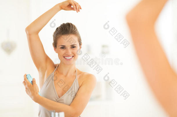 快乐的年轻女人在腋下涂抹除臭剂