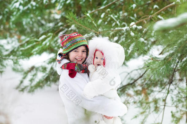 可爱的男孩在冬天的公园里拥抱他的小妹妹