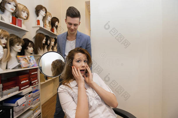 男发型师在沙龙里给忧心忡忡的女顾客展示头发