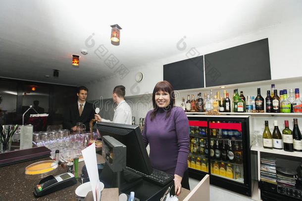 女<strong>收银员</strong>与经理和调酒师在酒吧柜台的肖像