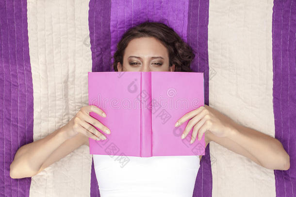 正上方的照片是一位妇女躺在有条纹的野餐毯子上，用书捂住脸