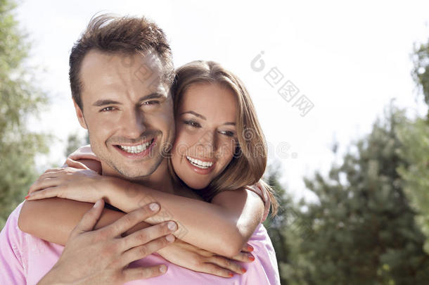一幅快乐的年轻人在公园里被女人从后面拥抱的画像